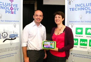 Kate and Joe holding a tablet in front of an 'inclusive technology Prize' sign